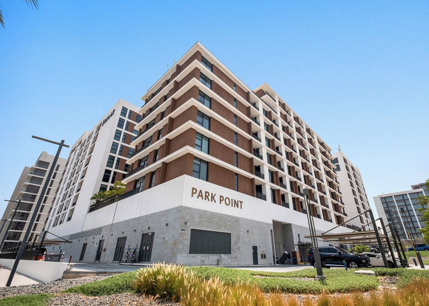 A multi-story building with the name 'PARK POINT' on the facade, featuring a modern architectural design with a mix of brick and white panels, and a flat roof.