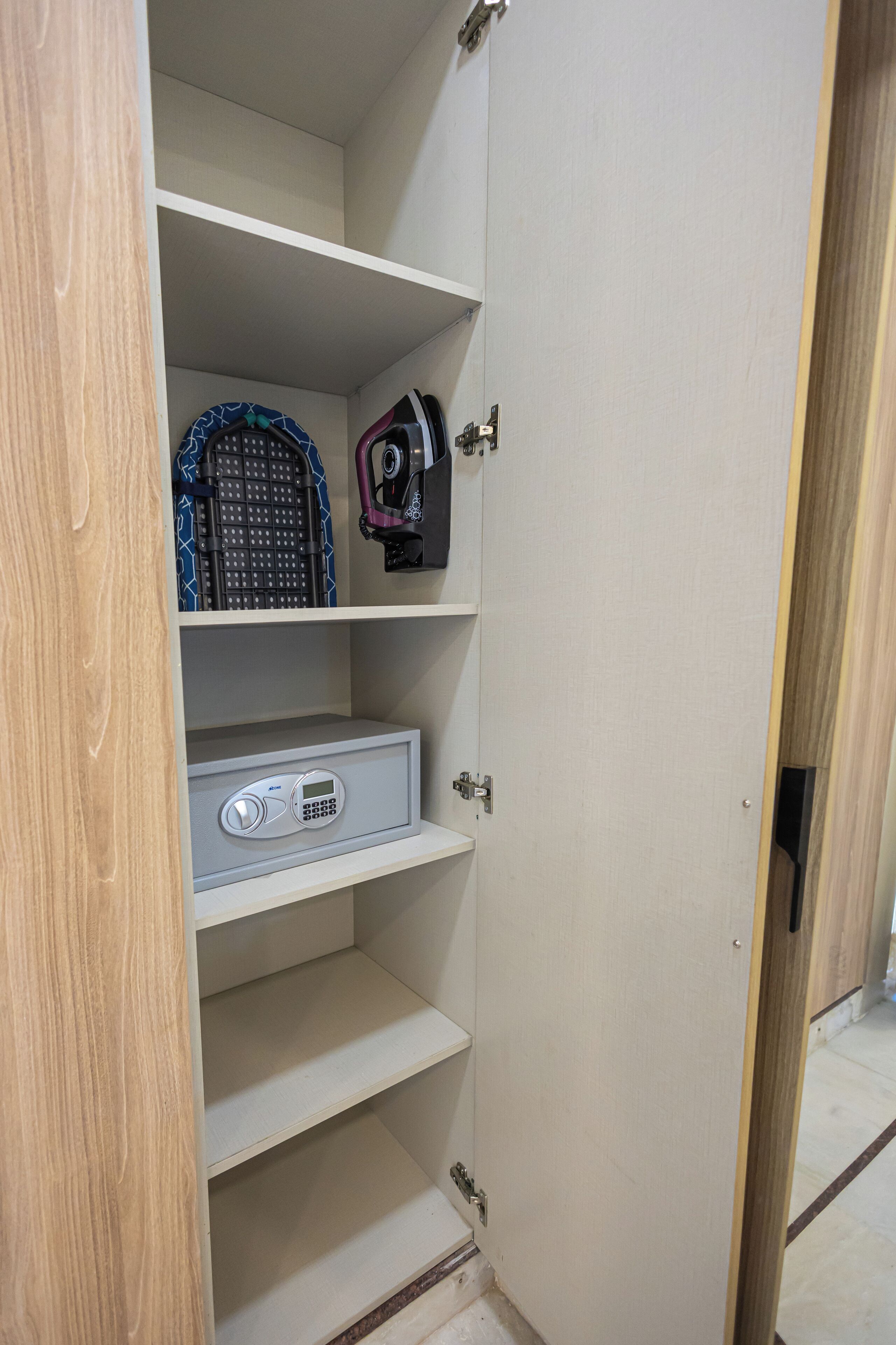 A wardrobe with multiple shelves, a small safe, and a baby stroller.