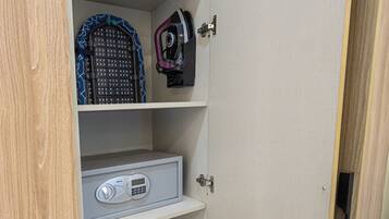 A wardrobe with multiple shelves, a small safe, and a baby stroller.