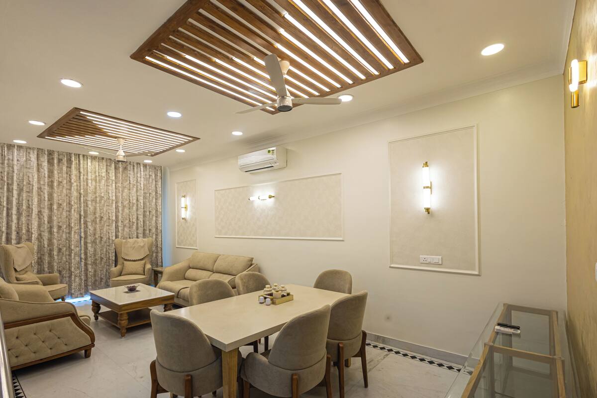 A modern hotel room with a dining area, a ceiling fan, recessed lighting, and a large window with curtains.