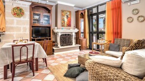 Un salon avec une cheminée, un téléviseur, une table à manger avec des chaises et un canapé.