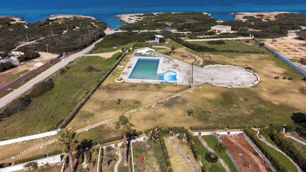 Vue aérienne d’une propriété dotée d’une piscine, d’espaces paysagers aménagés et offrant une vue sur l’océan.