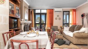 Un coin repas avec une table dressée pour quatre personnes, entouré de meubles en osier et d’un canapé.