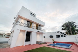 Un bâtiment moderne à deux étages, doté d’un balcon, d’une piscine et d’une pelouse bien entretenue.