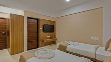 A hotel room with two beds, a TV, a ceiling fan, and a wooden wardrobe.