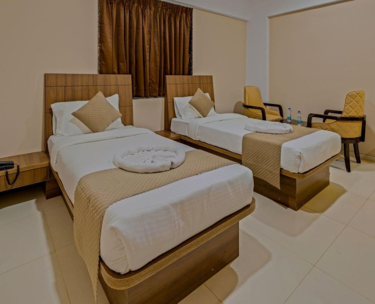 Une chambre d’hôtel avec deux lits, un bureau, une chaise et un rideau.