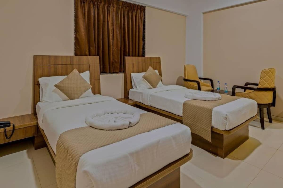 Une chambre d’hôtel avec deux lits, un bureau, une chaise et un rideau.