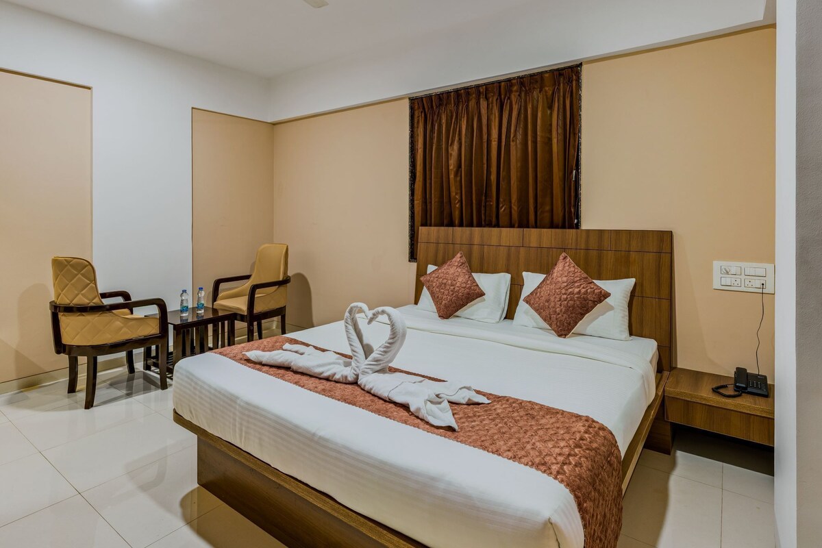 Habitación de hotel con cama, escritorio, silla, ventilador de techo y ventana con cortinas.