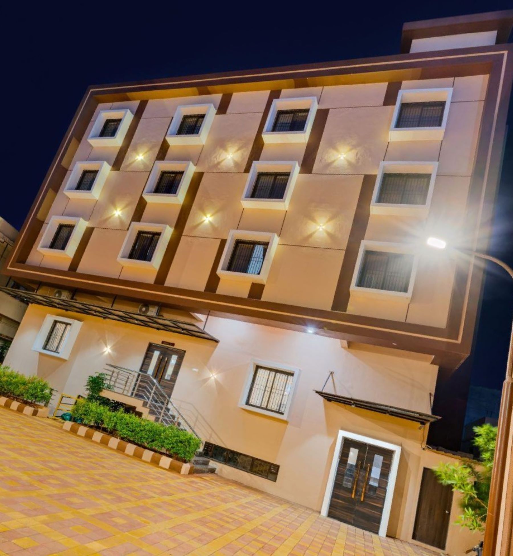 A multi-story hotel with a modern design, featuring a central staircase and a well-lit entrance.