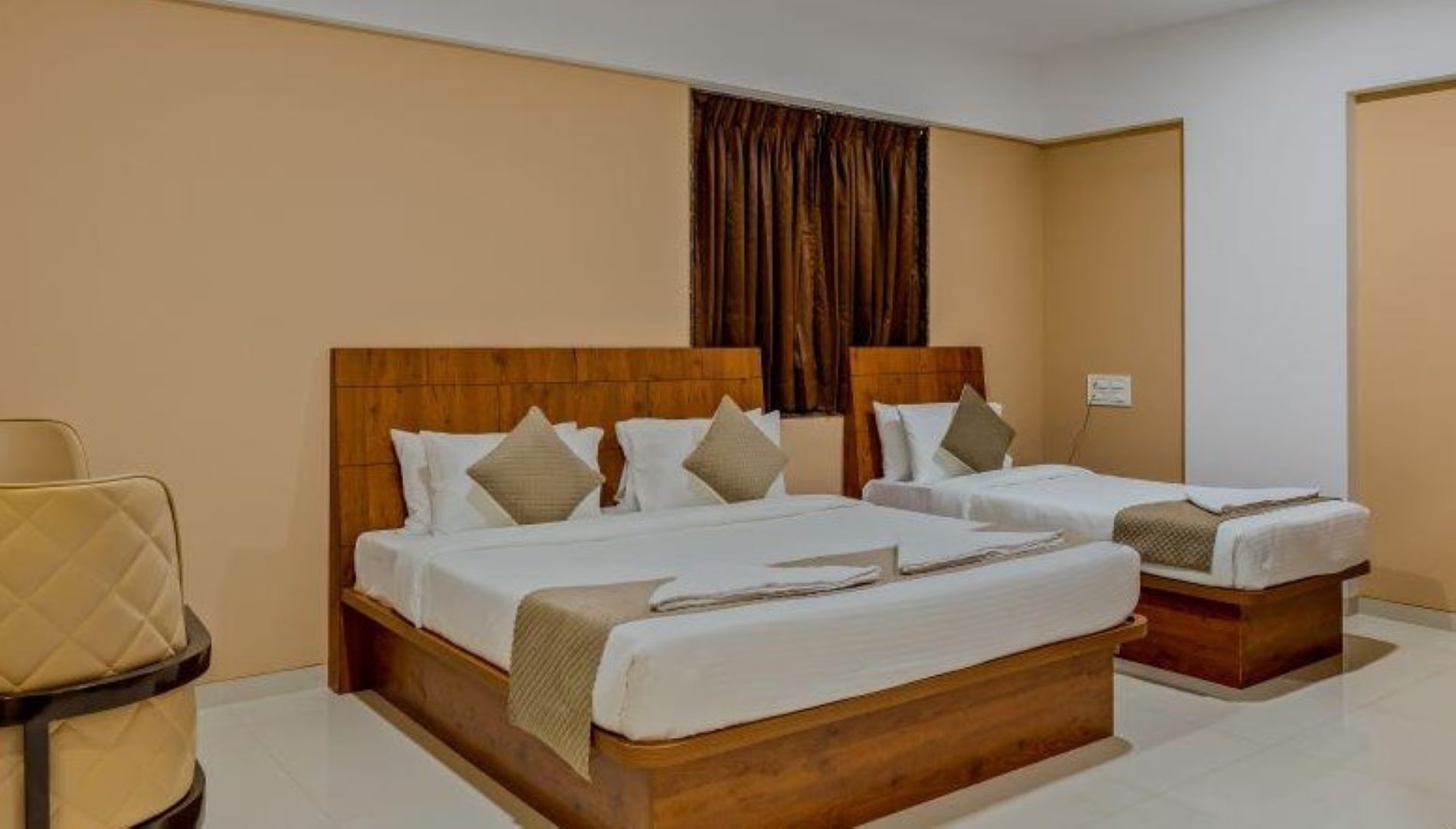 Une chambre d’hôtel avec deux lits, une tête de lit en bois et un mur de couleur beige.