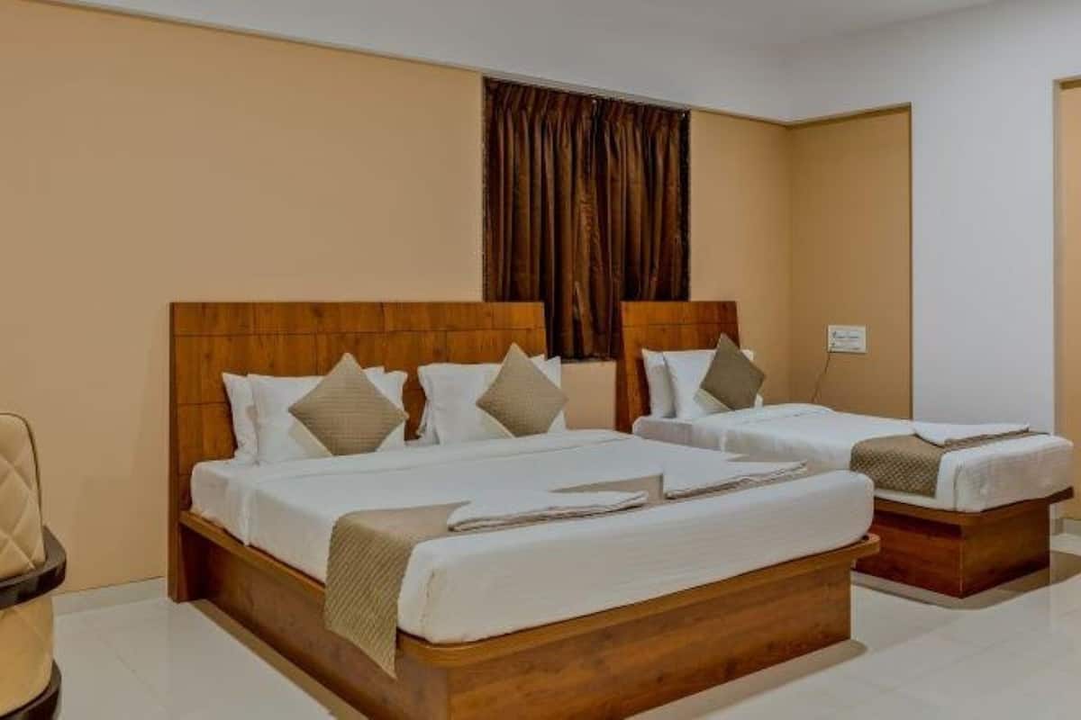 Une chambre d’hôtel avec deux lits, une tête de lit en bois et un mur de couleur beige.