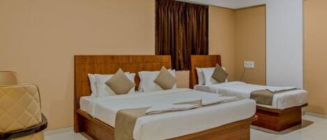 A hotel room with two beds, a wooden headboard, and a beige wall.