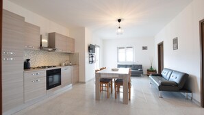Una cocina moderna con comedor, un sofá y un televisor montado en la pared.