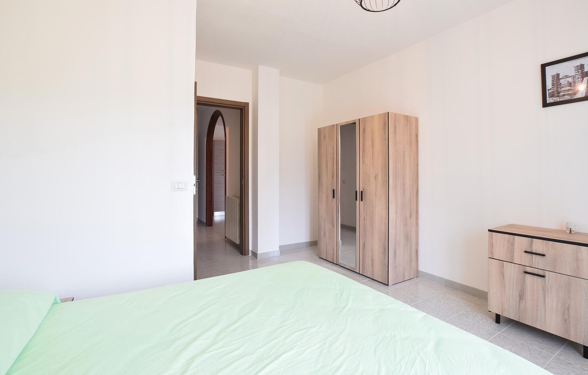 Une chambre à coucher avec un lit, une armoire et un tableau encadré au mur.