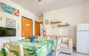 En matplats med ett bord för fyra personer, en tv och en dörr med en skylt som säger ”Rökning förbjuden”.