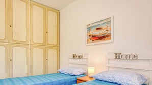 A bedroom with two beds, a painting of a boat on the wall, and the word 'Home' on the headboard. - Awesome apartment in Cogorno with WiFi (Cogorno)
