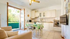 A modern kitchen with white cabinets, a dining area with a green tablecloth, and a ceiling fan. - Awesome apartment in Cogorno with WiFi (Cogorno)