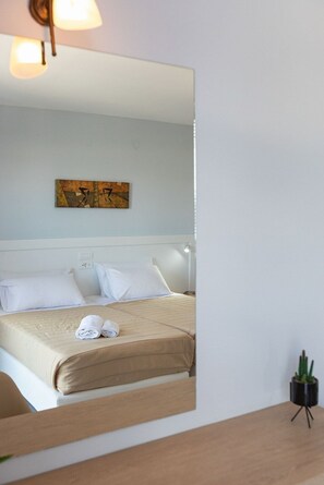 A hotel room with a bed, white pillows, a beige bedspread, and a small potted plant. - Armonia Hotel by Zante Plaza (Zakynthos)