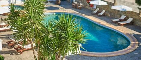 Alberca al aire libre, sombrillas en la alberca y camastros