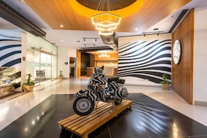 A modern interior with a zebra-striped scooter on a wooden platform, a 'Sunday' sign, and a unique ceiling design. - Sunday Hotel Chandigarh Zirakpur (Zirakpur)
