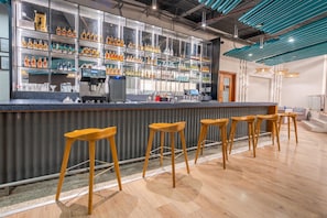 A bar area with a counter, multiple stools, and shelves stocked with bottles. - Sunday Hotel Chandigarh Zirakpur (Zirakpur)