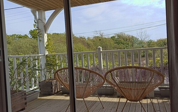 A wooden deck with two wicker chairs and potted plants.