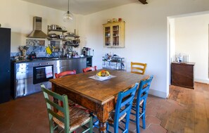 A kitchen with a wooden table, chairs, and a fruit bowl. There is a stove, oven, and cabinets. - 3 bedroom cozy home in Palazzo del Pero (Palazzo del Pero)