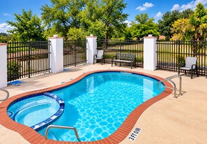 A swimming pool with a 3ft depth marker, surrounded by a fence, chairs, and a bench.