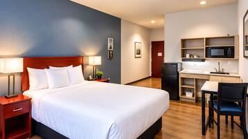 Habitación de hotel con cama, mesitas de noche, escritorio, silla, microondas y refrigerador.