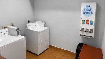 Un lavadero con dos lavadoras, un secador y un dispensador de jabón en la pared.