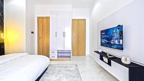Et moderne hotelværelse med seng, fjernsyn, garderobeskab og konsolbord.
