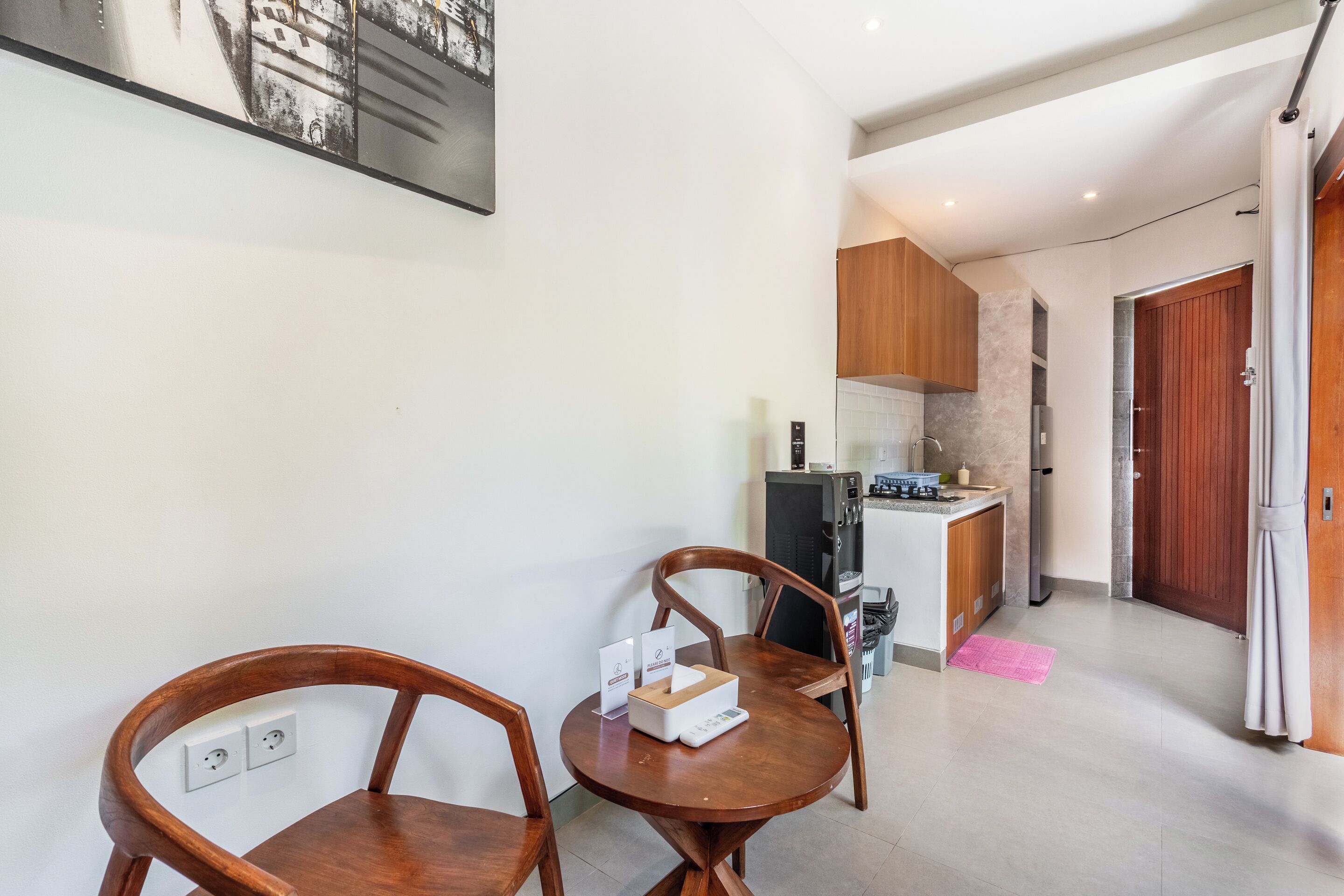 A dining area with two wooden chairs, a table, and a kitchen in the background.