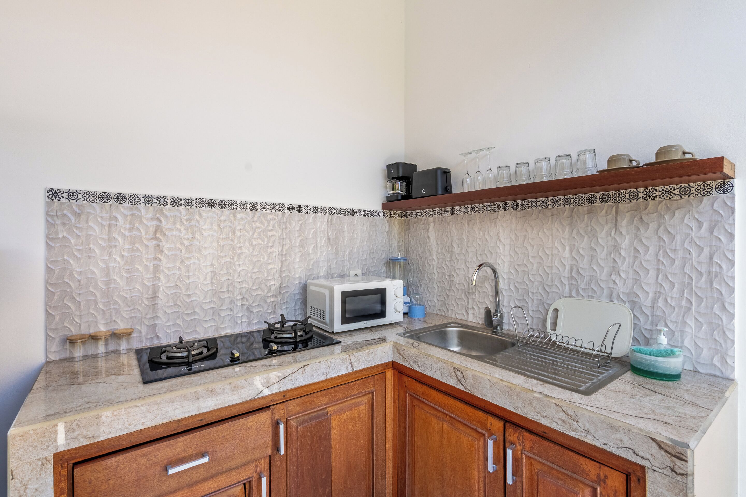 Una cocina equipada con microondas, estufa, fregadero y una repisa decorativa.