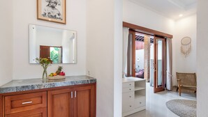 Un baño con encimera de mármol, armarios de madera, un espejo y un atrapasueños en la pared.