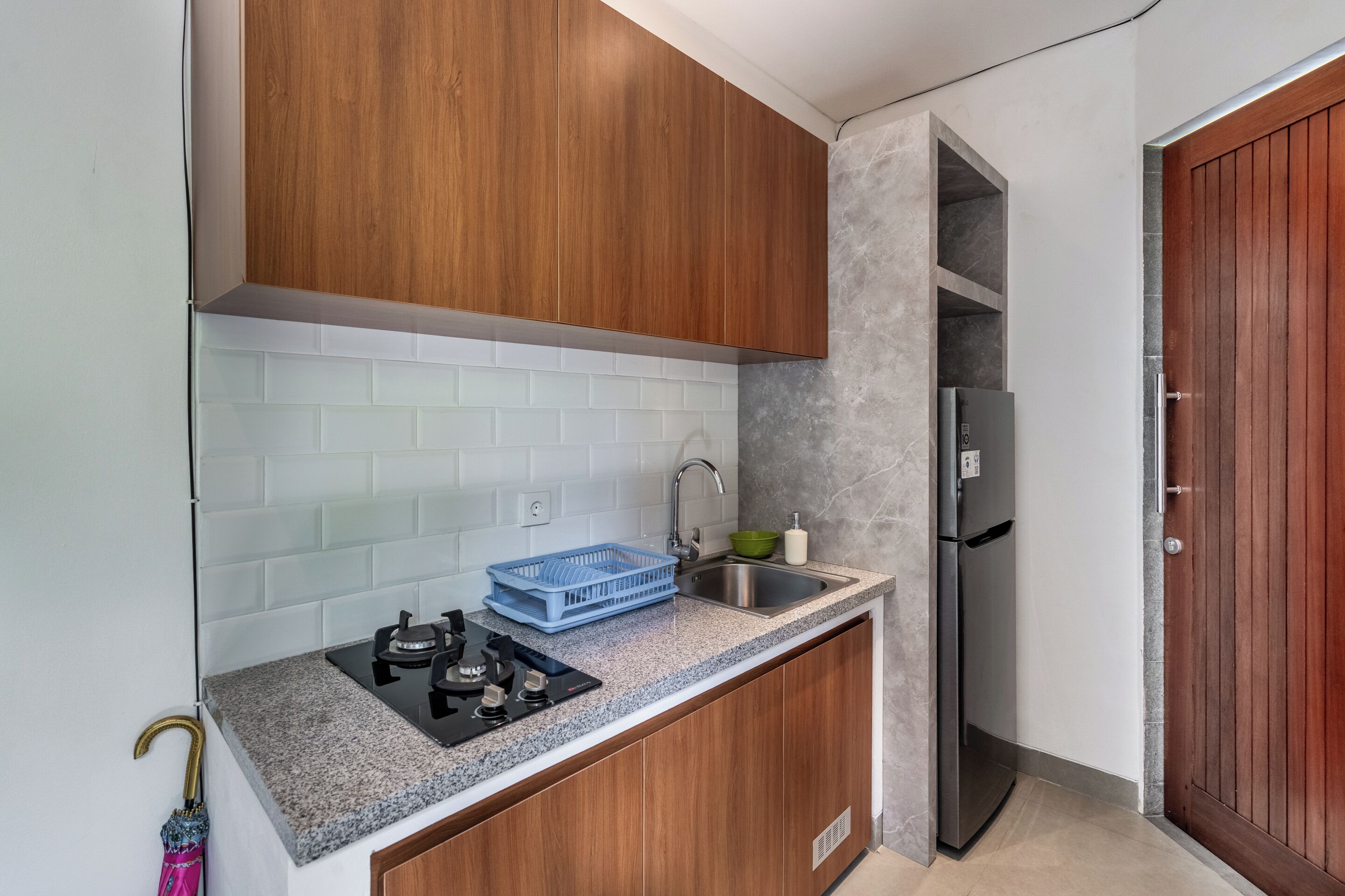 A kitchen with wooden cabinets, a stainless steel sink, a built-in oven, and a refrigerator.