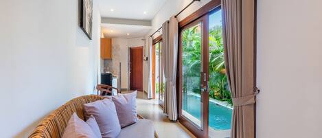 A modern interior with a sofa, a dining area, and a pool view.