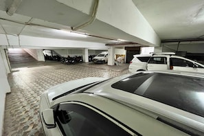 A multi-level parking garage with several cars and motorcycles parked.
