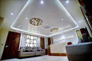 A modern lobby with a reception desk, a sofa, and a chandelier.