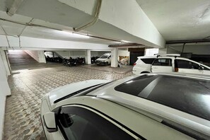 A multi-level parking garage with several cars and motorcycles parked.