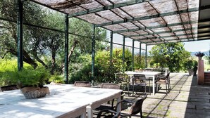Eine Terrasse im Freien mit überdachter Sitzgruppe, einem Tisch und Stühlen.