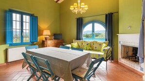 Una habitación con una mesa de comedor, sillas, un sofá, un televisor, una chimenea y vistas al exterior.