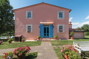 A two-story building with a pink facade, a blue door, and multiple windows with white shutters. - Le Due Querce - Vite (Cerreto Guidi)