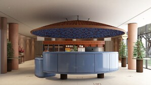 Ett modernt receptionsområde med ett centralt placerat receptionsbord, ett mönstrat tak och en skylt för incheckning.