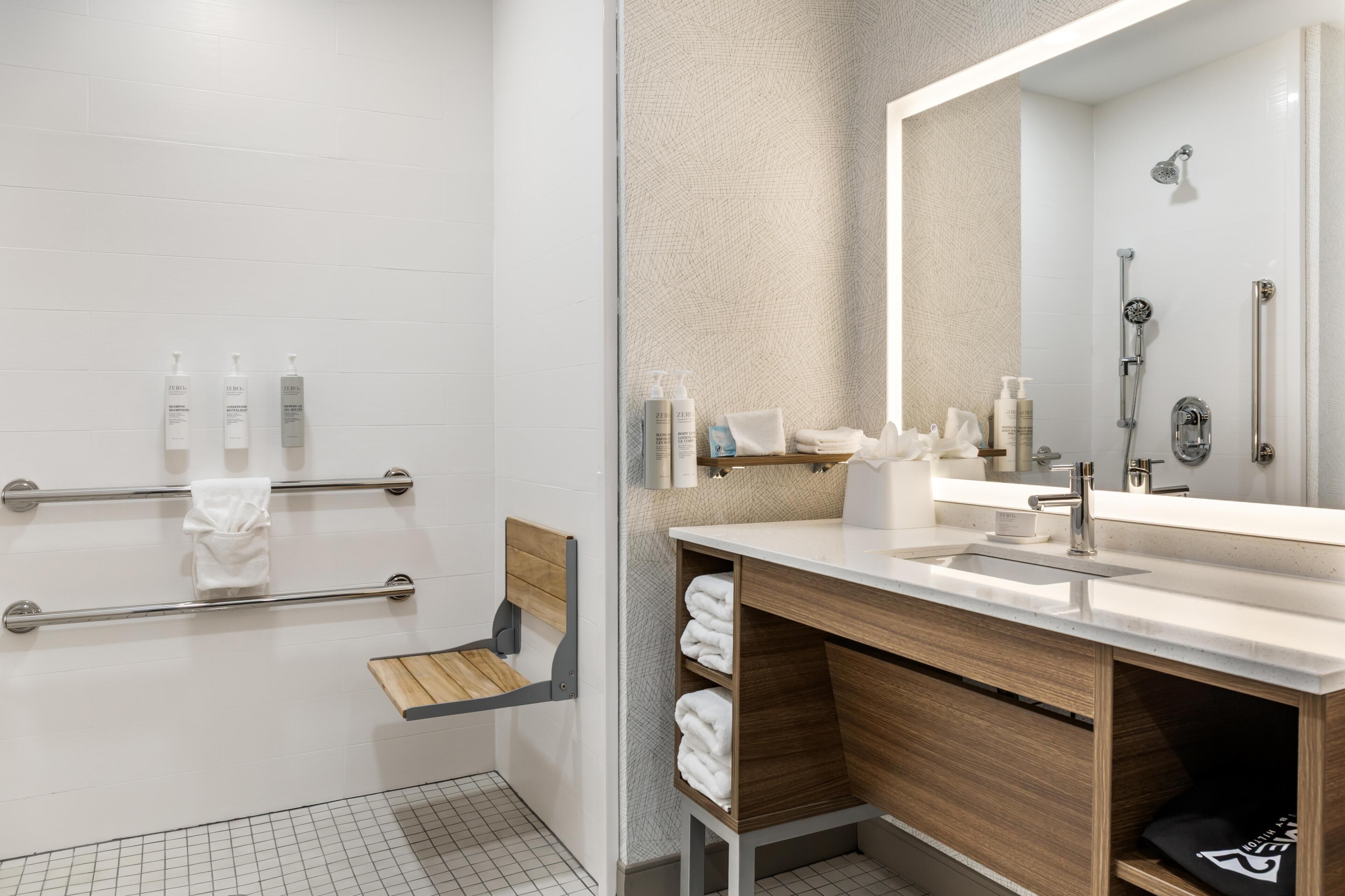 A modern bathroom with a shower, a sink with a mirror, and a towel rack.