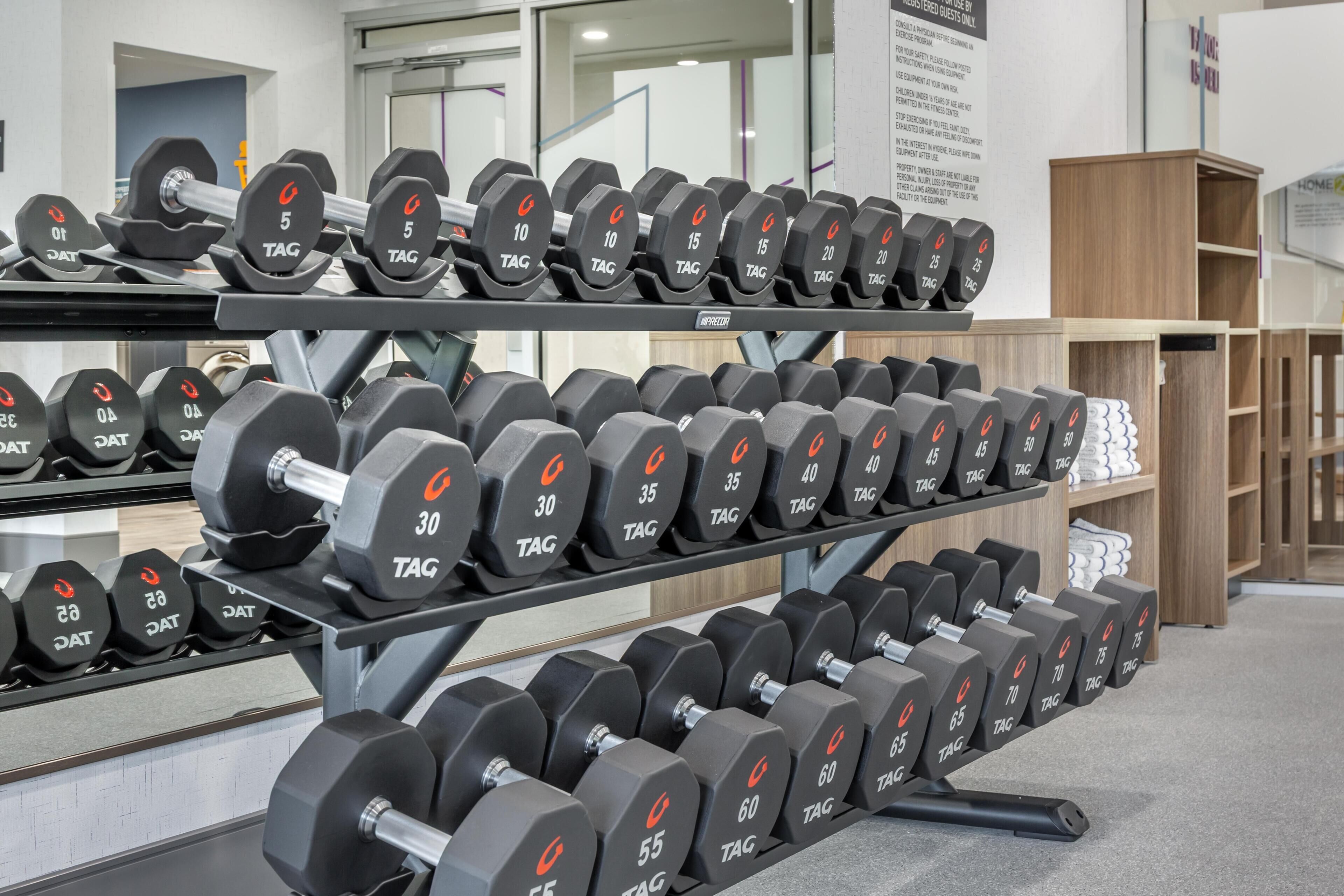 Un porte-haltères dans une salle de sport, avec différents poids disponibles.