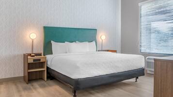 Una habitación de hotel moderna con una cama, mesitas de noche y una ventana.