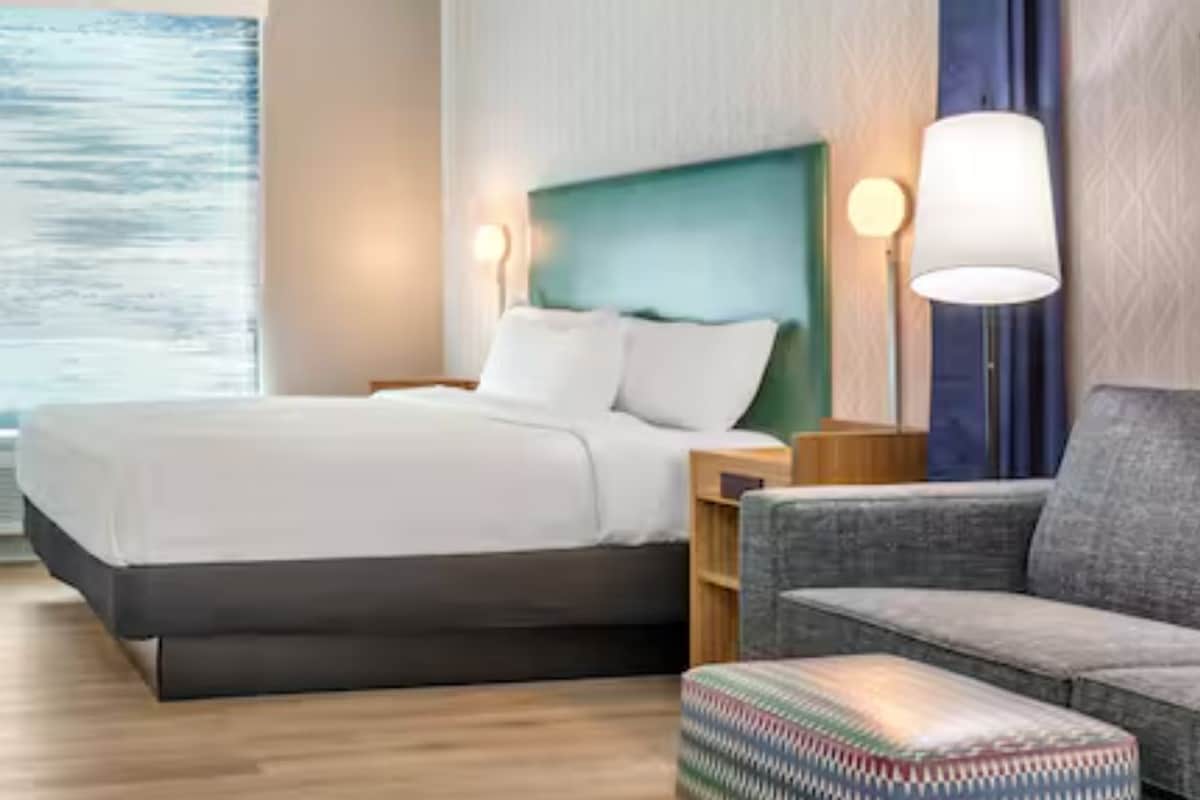 Hotellihuone, jossa on sänky, yöpöydät, työpöytä, tuoli ja ikkuna, josta on näkymä.
