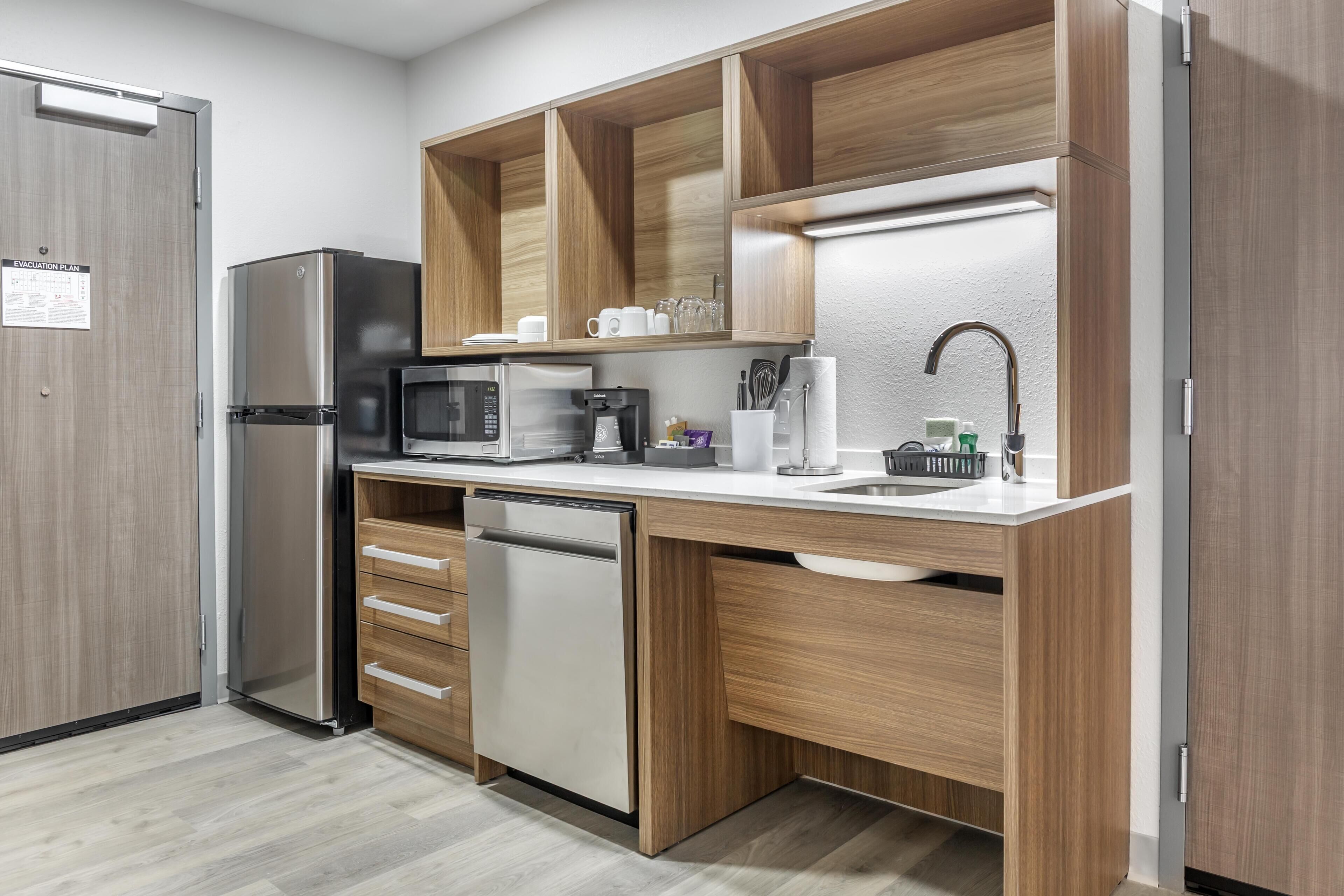 A compact kitchen with a refrigerator, microwave, coffee maker, and dishwasher.