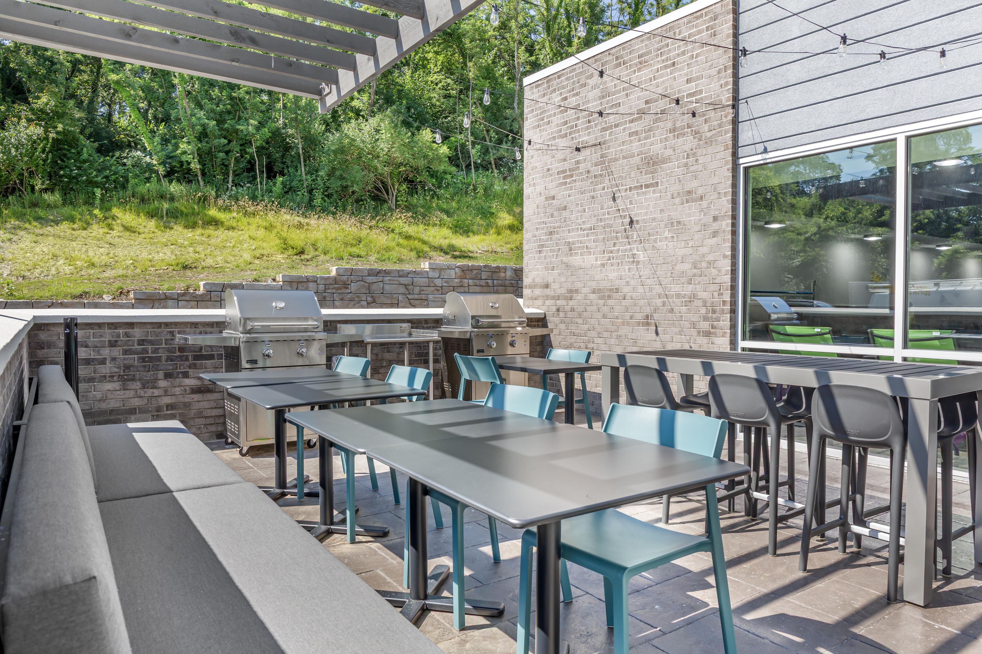 An outdoor patio with a brick wall, a grill, and seating.