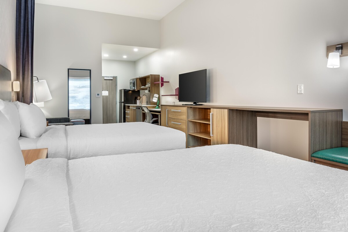 Une chambre d’hôtel avec deux lits, un bureau, une télévision et un miroir.